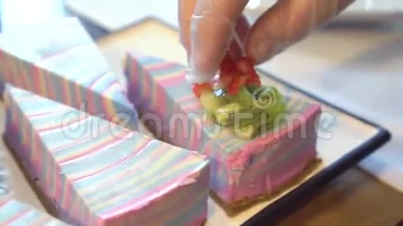 糖果手用猕猴桃和草莓装饰彩色芝士蛋糕视频的预览图