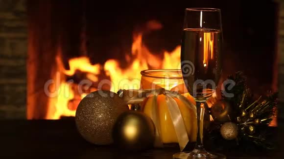 在壁炉旁的桌子上放圣诞球蜡烛和一杯香槟视频的预览图