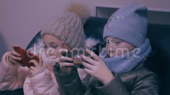两个穿着冬装看手机玩游戏的少女视频的预览图