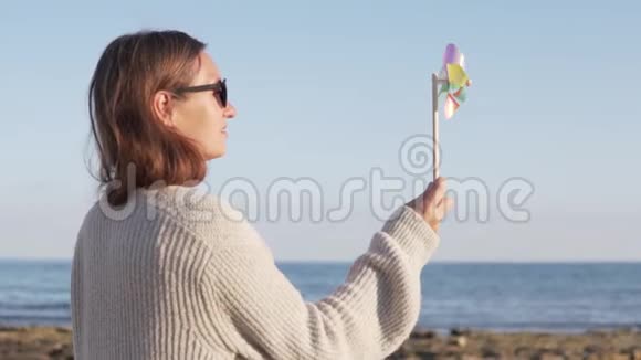 可爱的快乐女孩在海滩上玩风车的肖像视频的预览图