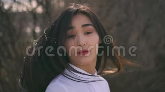 美丽的年轻亚洲女孩转向相机风轻轻地吹动她的头发视频的预览图