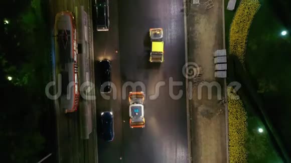 夜间工作人员在城市铺设沥青的空中镜头路边的汽车交通视频的预览图