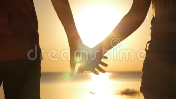 日落时分一对情侣牵着手在海边散步视频的预览图