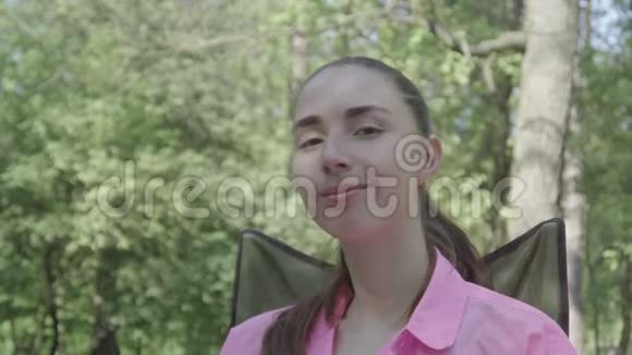 年轻的女人坐在森林里的椅子上微笑视频的预览图