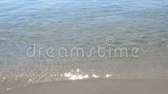 海浪和阳光的特写镜头冲刷着沙滩的海岸视频的预览图