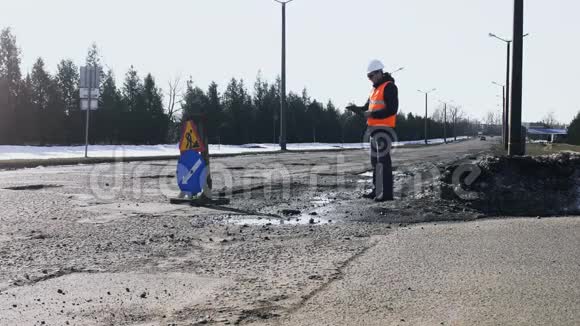 工程师或建筑工人看检查道路坑并在平板上写笔记修理工作的标志在路边沥青上视频的预览图