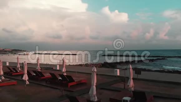 带着日光浴床和带海的雨伞的无人机在海滩上空飞行视频的预览图