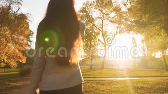 留着长发的女孩正站在公园里晒着夕阳打着电话日落时分穿裙子的女人的屁股视频的预览图