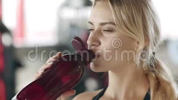 微笑的运动女性在健身健身房喝水快乐的女孩在喝水视频的预览图