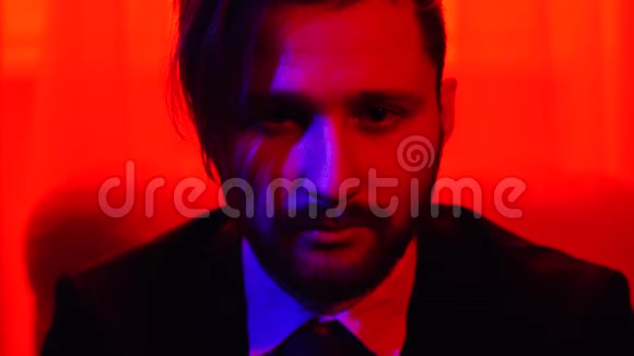 一个穿着商务服坐在明亮的红光中的商务胡子微笑男人的肖像视频的预览图