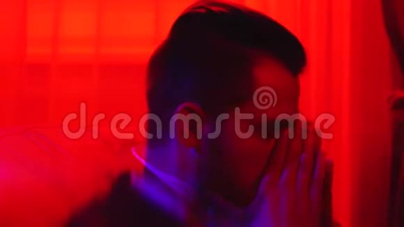 一个疲惫的胡须男坐在椅子上的肖像在明亮的红光中被隔离疲惫的上班族视频的预览图