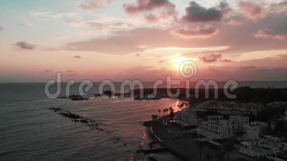 在日落时用棕榈汽车酒吧和酒店俯瞰活动旅游区日落时分城市港湾的无人视野视频的预览图