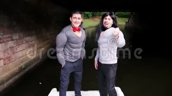两个穿着假肌肉垫服的家伙在桥下的船上跳舞视频的预览图