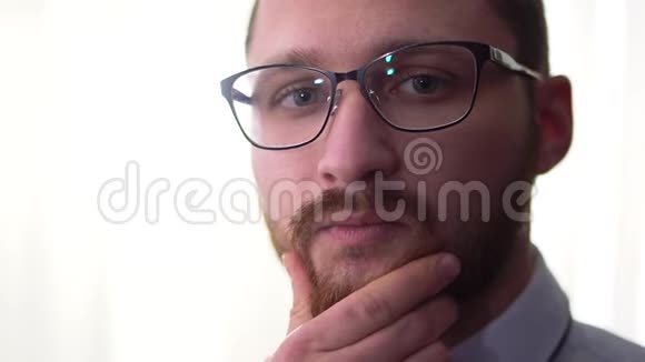 一个忧郁的英俊留着胡子的商人的肖像戴着白色背景特写的眼镜视频的预览图