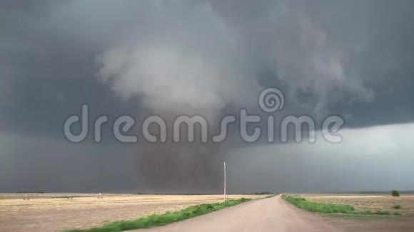 一个巨大的危险的龙卷风在一片黑暗的风暴云下把泥土高高地飘向天空视频的预览图