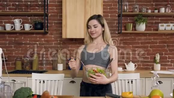 漂亮的女孩在厨房的碗里放了绿色沙拉视频的预览图