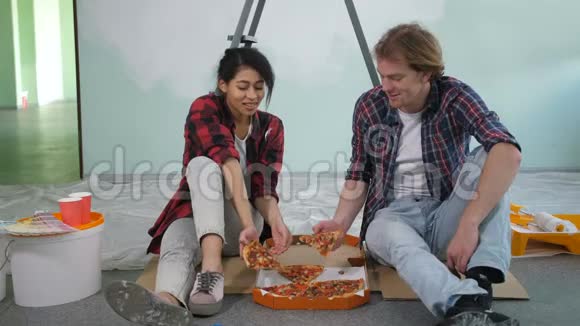 快乐的一对夫妇在装修时吃披萨视频的预览图