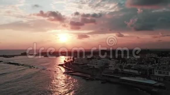 有风的大海和码头的日落的无人机顶视图海浪冲击海岸城市港湾的无人机射击视频的预览图