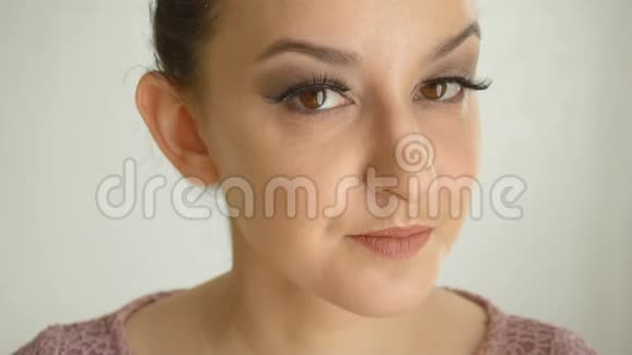长睫毛和棕色眼睛的女孩会接吻可爱的女性模特白色背景的时尚化妆视频的预览图