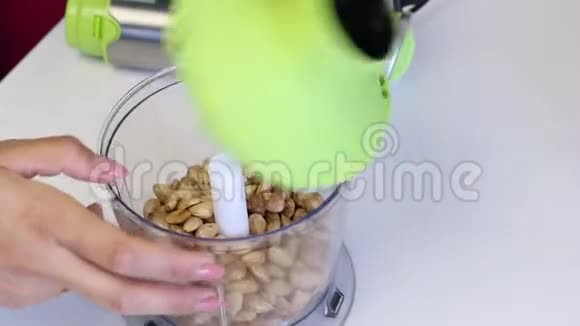 在搅拌机碗里剥杏仁磨一个女人用盖子盖上碗并装上搅拌机烹饪釉料视频的预览图