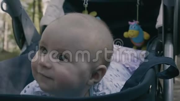 慢动作婴儿车里的小男孩趴在肚子上微笑视频的预览图