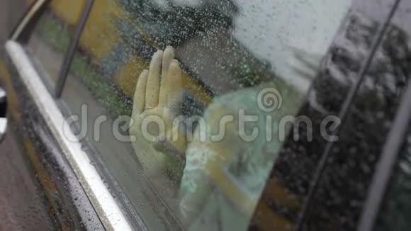 那个女孩把手掌放在汽车的湿玻璃上视频的预览图