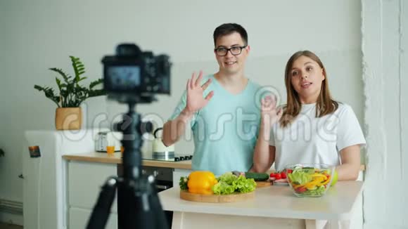 女孩和男人在家里厨房用摄像机录制关于有机食品的视频视频的预览图