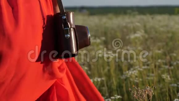 穿着红色裙子的女人在夏天的一片美丽的田野里漫步视频的预览图