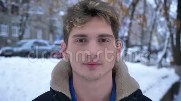 雪天穿着冬衣站在户外的年轻白种人男性迷人的特写镜头视频的预览图