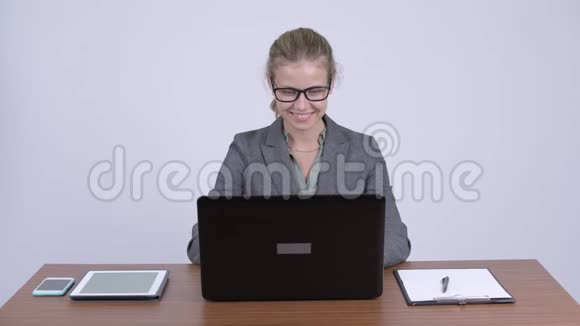 年轻快乐的金发女商人一边工作一边思考着笔记本电脑视频的预览图