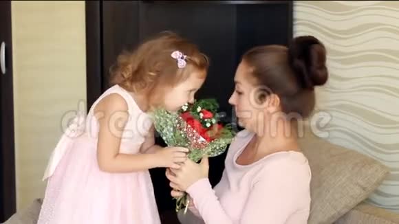 妈妈今天女人和她的孩子女孩带着一束玫瑰微笑着嗅着芳香的花朵视频的预览图