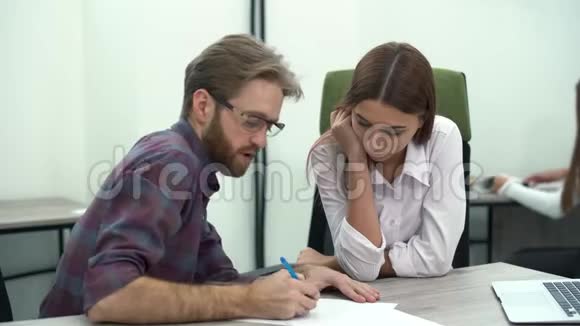 长胡子的经理戴着眼镜一边和他的员工坐在桌子旁一边写着一份纸开发计划创意创意视频的预览图