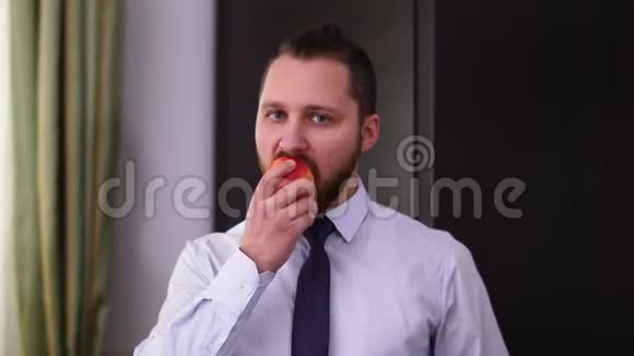 一位成功留胡子的商人穿着一件衬衫带着领带吃苹果的肖像健康生活方式的概念视频的预览图