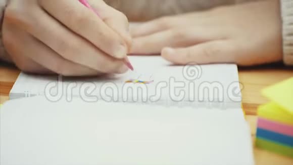 有创造力的孩子的手她的笔记本上用粉红色铅笔画画视频的预览图