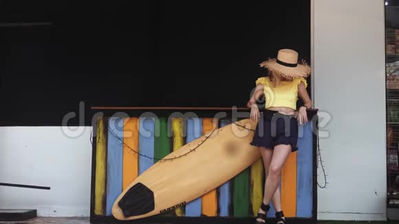 穿短裤和草帽的年轻美女站在冲浪板旁边视频的预览图
