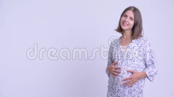 快乐的年轻孕妇拍打手指展示一些东西视频的预览图
