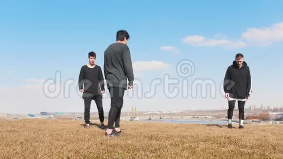 三个年轻人在草地上同步表演杂技表演视频的预览图