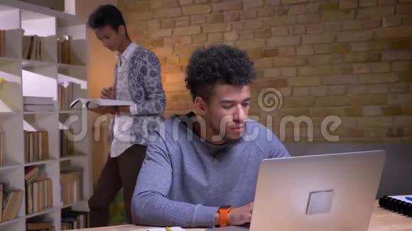 两名不同种族的学生在图书馆一起学习的特写镜头非裔美国男性使用视频的预览图