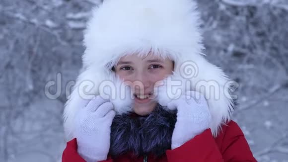戴着白色蓬松帽子的女孩在寒冷的霜天微笑圣诞节假期特写视频的预览图