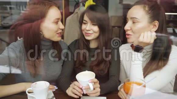 女朋友在咖啡馆里聊天喝饮料玩得很开心从玻璃后面看视频的预览图