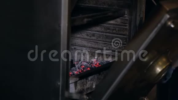 一名男子在餐厅的专业烧烤炉中混合煤的特写镜头视频的预览图
