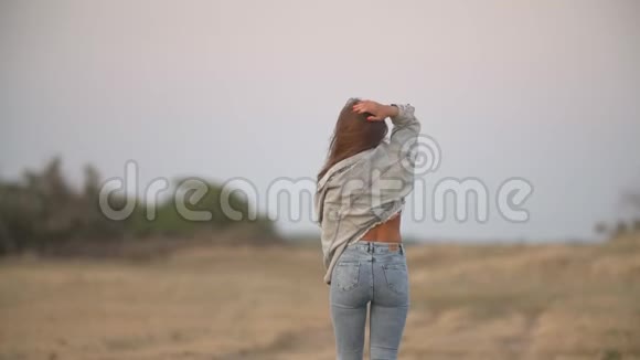 穿牛仔裤的女孩在大自然中行走视频的预览图