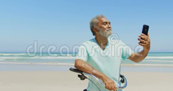 活跃的非裔美国人在海滩上用手机自拍的正面景色视频的预览图