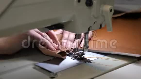 女裁缝在缝纫车间缝制黑色皮革两针缝纫机上下快速移动特写视频的预览图