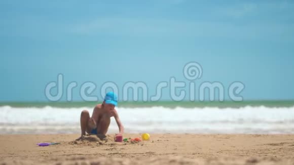 一个小男孩正在大海上的沙子里玩耍小腿和手指大海的背景是黄沙和碧水视频的预览图