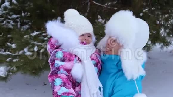 妈妈把小女儿抱在怀里冬天在公园的白雪上散步微笑着儿童和母亲视频的预览图