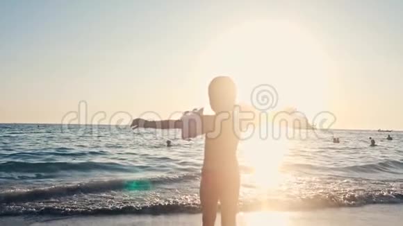 快乐的孩子在美丽的夕阳下跑进大海的剪影婴儿在沙滩向水冲去后方视频的预览图