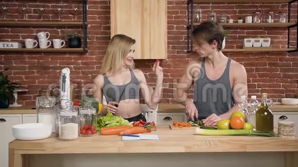 快乐的年轻女人一边给男朋友喂辣椒一边切蔬菜做沙拉健康饮食视频的预览图