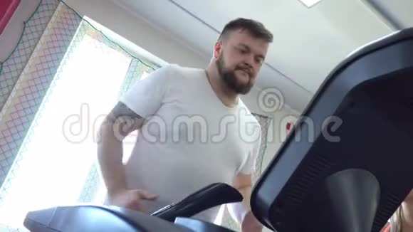 肥胖的白种人留着胡子在健身房的跑步机上跑步运动有氧运动视频的预览图