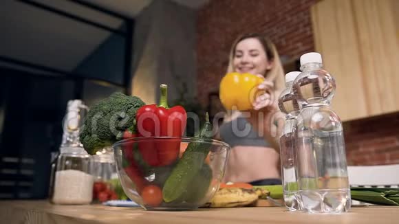 年轻快乐的女人在碗里放黄色的辣椒里面有新鲜的蔬菜和水果西兰花黄瓜红辣椒视频的预览图